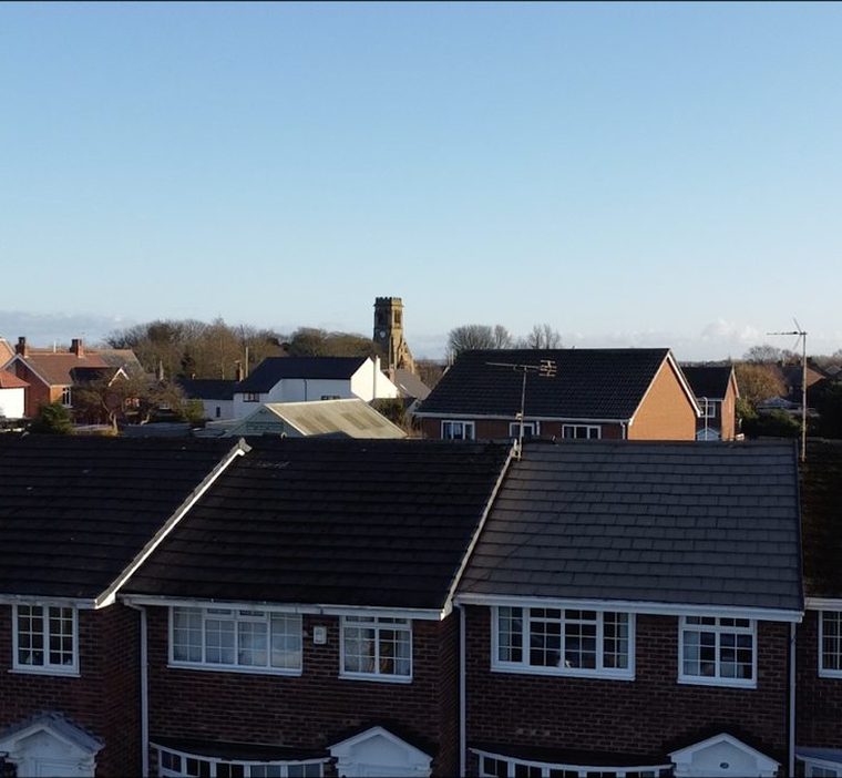 Rooftops in Crossens, Southport on a clear day, with the church tower in the distance