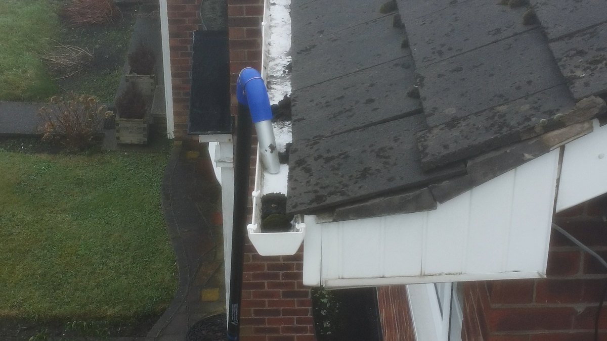 Vacuum pole reaching up to a blocked gutter at roof height on a house in Crossens