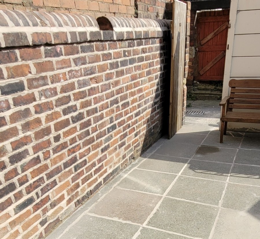 The same wall repointed, new mortar brought out flush through every course up to the coping