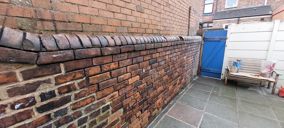 Old brick garden wall in Eccleston with worn, eroded mortar joints before repointing