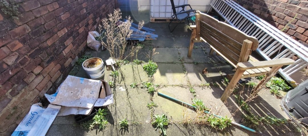 Rear patio in Eccleston, St Helens, overgrown with weeds rooted in the failed joints before work started