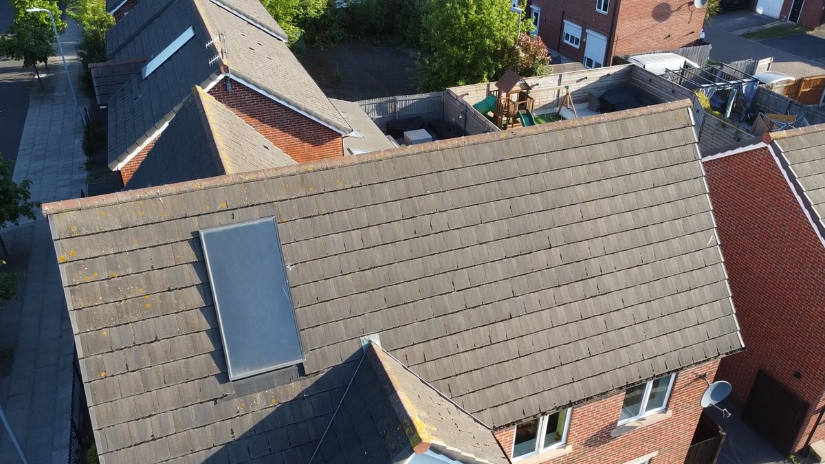 Drone view of a large detached roof in Bootle before cleaning, yellow lichen spotted across the tiles and a solar panel set into the slope