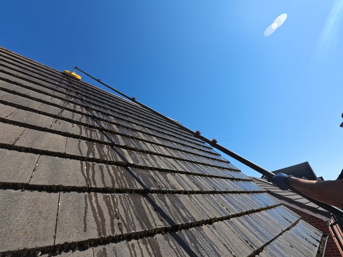 Looking up the Bootle roof mid-clean, moss still packed along the tile courses with washed streaks running down where the head has passed